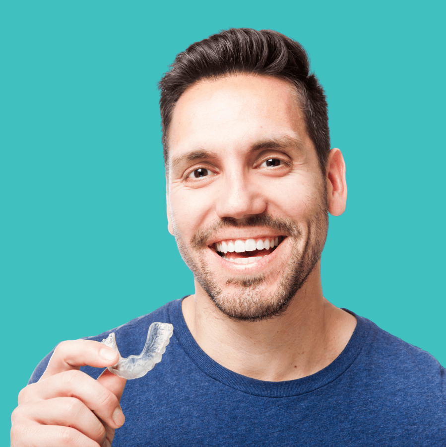 Smiling man holding a clear Invisalign aligner