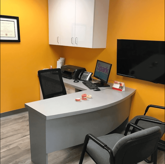 Front desk with an orange accent wall at the Spark Orthodontics Lancaster, PA office