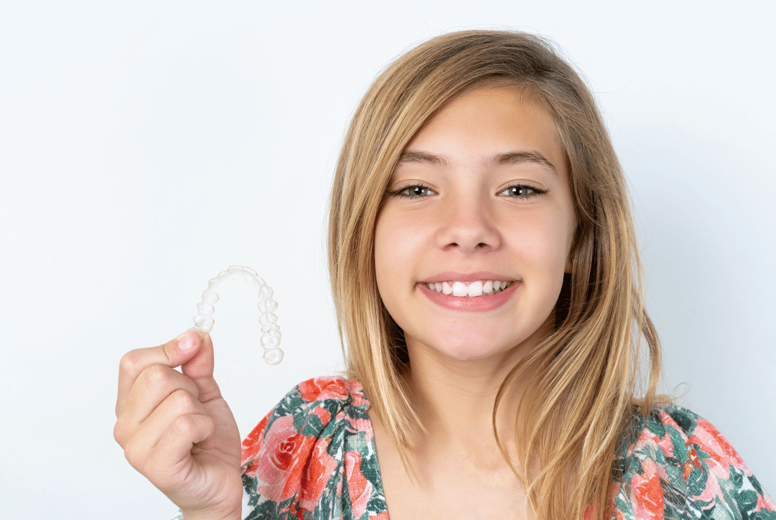 Teenage girl holding clear orthodontic aligners