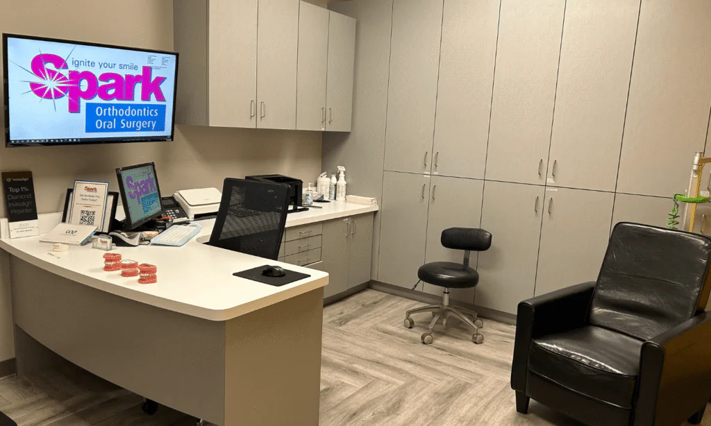 Front desk with a Spark Orthodontics logo displayed on a wall-mounted screen at the Hazleton, PA office